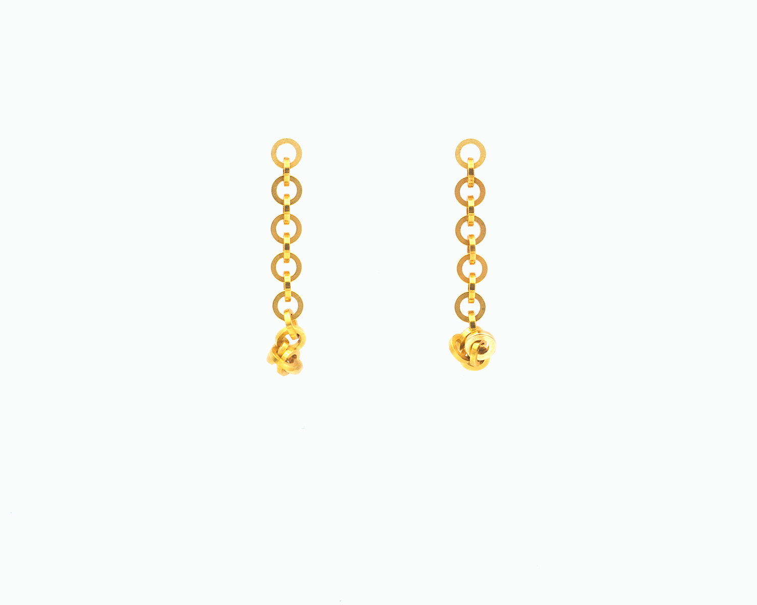 Zu sehen ist hier ein hängendes Ohrschmuck-Paar. Es sind zwei mit der Vorderseite nach vorne zeigende und nach unten hängende Kettenstücke aus ineinander eingehängten Kreisringelementen mit Vierkantprofil. Am unteren Ende sind ein paar Kettenelemente jeweils an den unten sitzenden Magneten angedockt. Dies ist eine der vielen Tragemöglichkeiten dieses Ohrschmuckes. Der Ohrschmuck ist goldfarben. Er ist aus Edelstahl, Feingold plattiert.