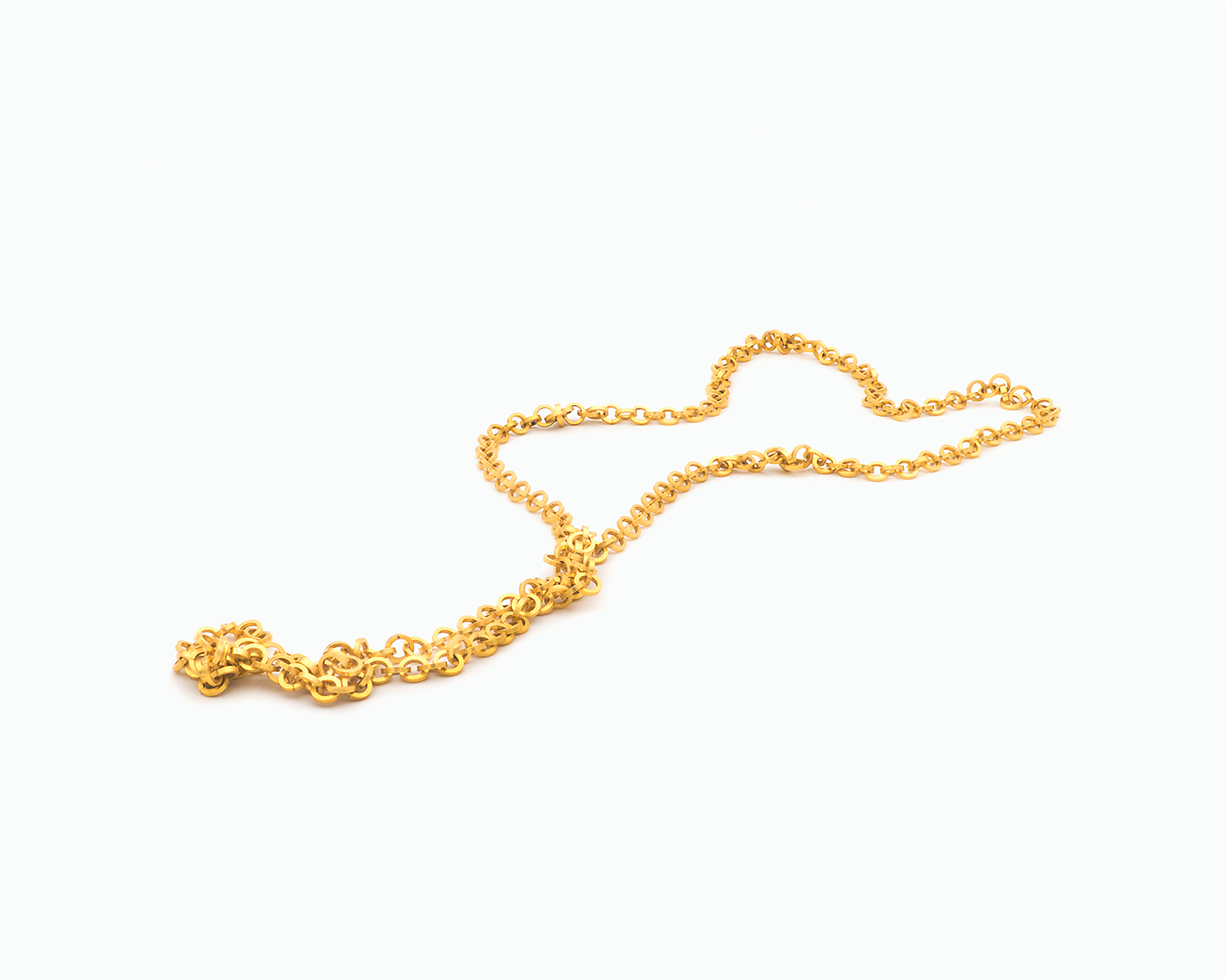 Zu sehen ist hier eine Kette aus runden, vierkantigen Ring-Elementen. Die Kette ist liegend in einer Tragevariante dargestellt, bei der die Kette am Dekolleté zusammenkommt und dann in einem Strang nach unten abschließt. Dies ist eine der vielen Trageoptionen dieser wandelbaren Kette. Die gesamte Kette ist goldfarben (Feingold plattiert).