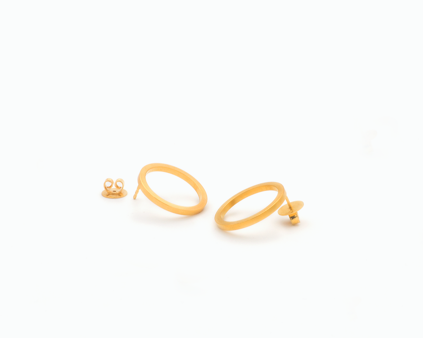 Zu sehen ist hier ein Ohrschmuck-Paar. Es sind zwei in unterschiedlicher Perspektive liegende, circa münzgroße, kreisförmige Ringe mit Vierkantprofil, an deren Rückseiten jeweils der Steckerstift sitzt. Beim linken Ohrschmuck liegt der Rückstecker daneben, beim rechten Ohrring steckt er auf dem Stift. Der Ohrschmuck ist goldfarben. Er ist aus Edelstahl, Feingold plattiert.