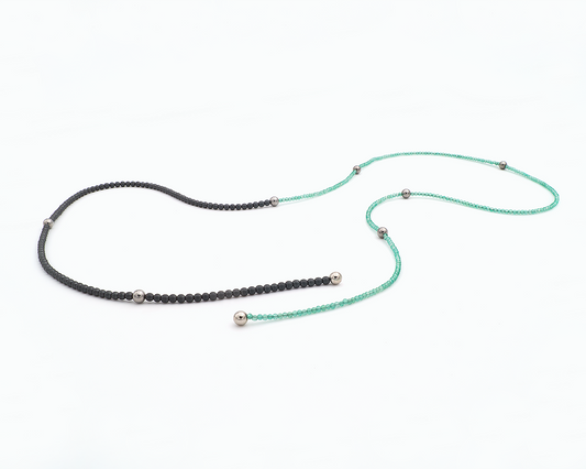 Zu sehen ist hier eine Kette aus etwas größeren dunkelgrauen, matten Hämatitkugeln und etwas kleineren grünen, facettierten Achatkugeln. Dazwischen sitzen Edelstahlkugeln und an den Enden Magnetkugeln. Die Kette ist offen und leicht kurvig liegend dargestellt. Dies ist eine der vielen Tragevarianten dieser wandelbaren Kette.