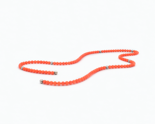 Zu sehen ist hier eine Kette aus Bambuskorallekugeln. Dazwischen sitzen Edelstahlkugeln und an den Enden Magnetkugeln. Die Kette ist offen und leicht kurvig liegend dargestellt. Dies ist eine der vielen Tragevarianten dieser wandelbaren Kette.