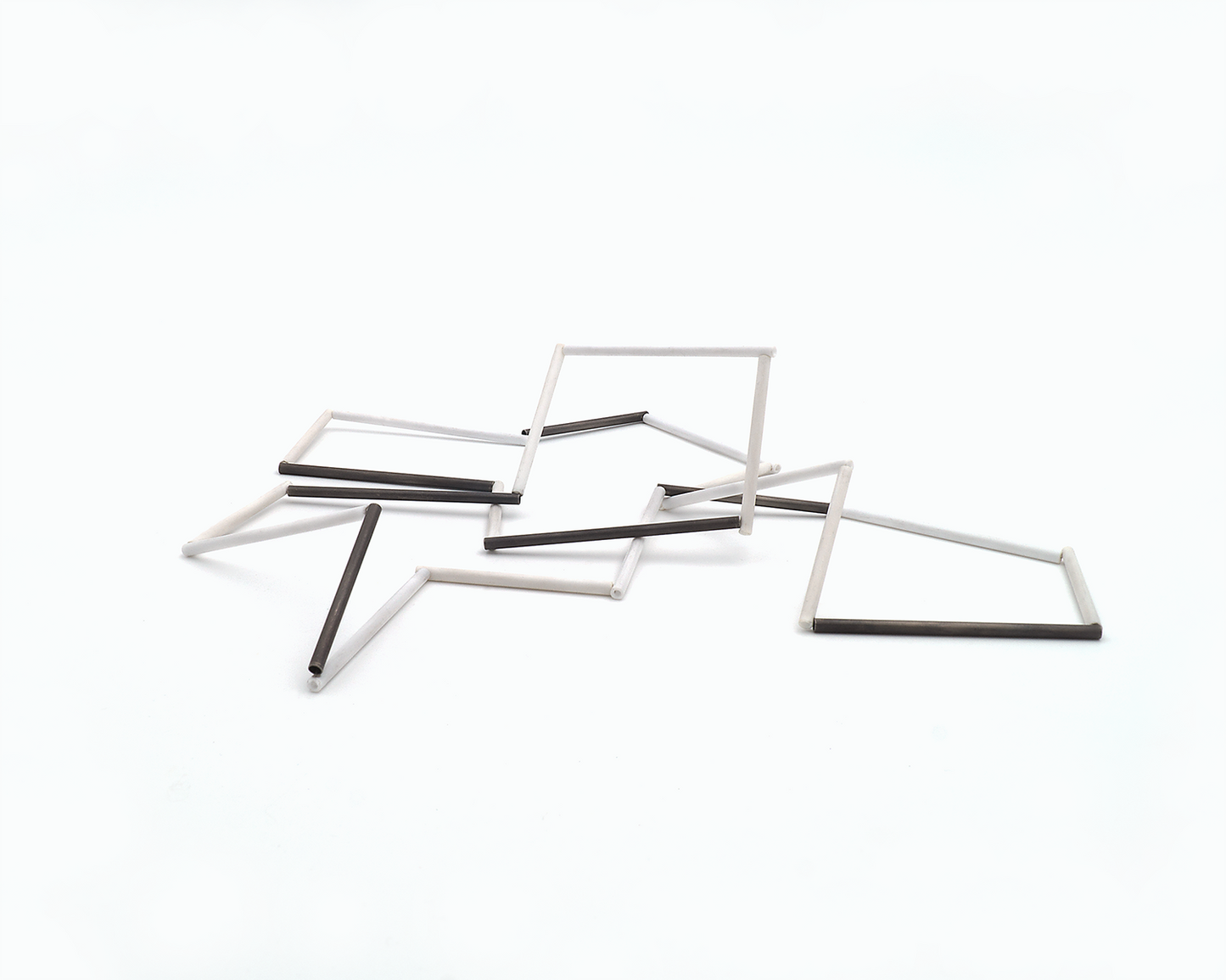 Zu sehen ist hier eine liegende Kette mit weißen und schwarzen Stäben. Die Stäbe sind Rohrabschnitte in zwei verschiedenen Längen. Die Kette hat eine grafische Anmutung, bei der die Linie als Hauptakteur dominiert.