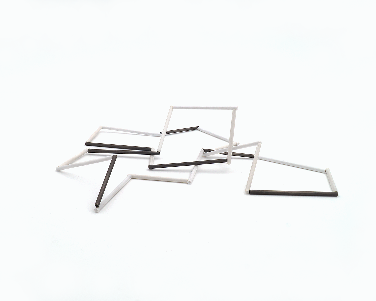 Zu sehen ist hier eine liegende Kette mit weißen und schwarzen Stäben. Die Stäbe sind Rohrabschnitte in zwei verschiedenen Längen. Die Kette hat eine grafische Anmutung, bei der die Linie als Hauptakteur dominiert.